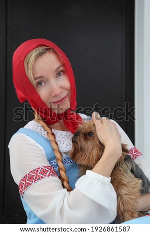 A woman in a Russian suit with a dog in her arms. Cosplay for the fairy tale Morozko. High quality photo
