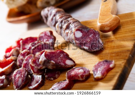 Traditional French thin dry cured sausage sliced on wooden surface
