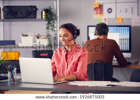 Business Team Wearing Telephone Headsets Talking To Callers In Customer Services Department