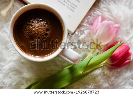 Book, coffee and tulips on a white furry carpet