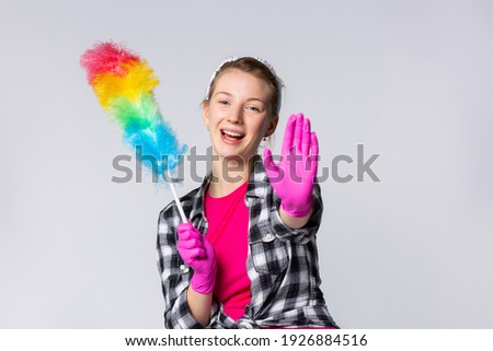 Smiling housewife holding dust brush. Woman clean dust. Cleaning service household concept, gray background with side space
