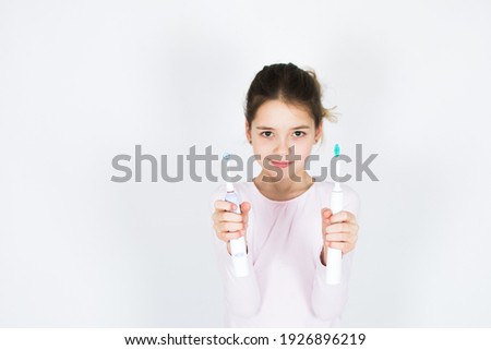 Young girl can´t decide between sonic and rotating oscillating toothbrush isotated on white background. Oral care and white teeth concept with copy space.