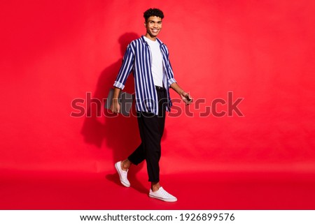 Full length profile side photo of young african man go walk meeting hold laptop isolated over red color background