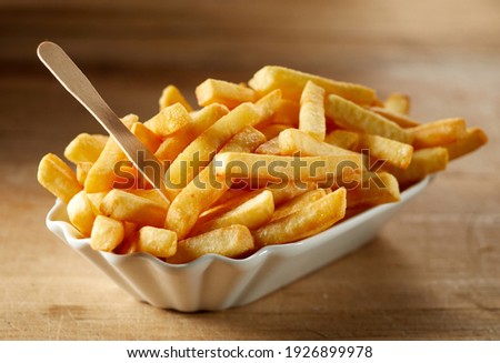 Tasty deep fried potato slices with organic fork in ceramic bowl on wooden table in sunlight Royalty-Free Stock Photo #1926899978