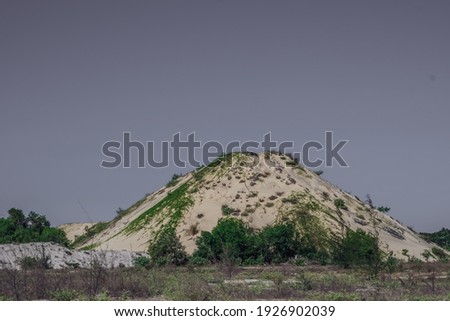 Copy space above Mountain volcano shape. White sand, blue purple clear sky, foliage bushes trees. Beautiful nature background design for screensaver wallpaper web. Mystic, evening mood concept