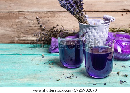 Lavender tonic drink on wooden table. Natural organic flower drink for morning good mood, dry bouquet, fragrant candle, copy space