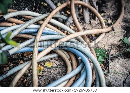 Close-up shot garden irrigation dirty blue pink hose bundle lie down on ground. Concept of gardening, pastime, water supply, communications