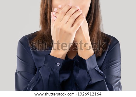 The woman in a dark blue shirt not commenting and refusing. woman with her hands on her mouth because of bad breath or halitosis Royalty-Free Stock Photo #1926912164