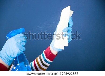 Surface home cleaning spraying antibacterial sanitizing spray bottle. Disinfecting against COVID-19 spreading, wearing medical blue gloves.