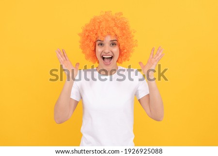 extremely happy funny girl with fancy look wearing orange hair wig on yellow background, happiness.