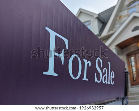 Sign for sale in front of a detached house in residential area. Real estate bubble, new listings, hot housing market, overpriced property, overpaid, buyer activity, spring and summer sale  concept.