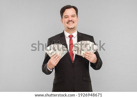 Career, corruption, mafia or work concept. Man in suit holding many dollars. Indoor, studio shot, isolated on gray background
