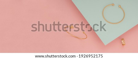 Top view of golden jewelries on pink and green