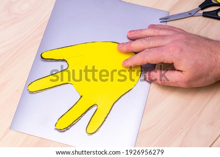cut out of a sheet of yellow paper, the palm for making an Easter bunny lies on the table. High quality photo