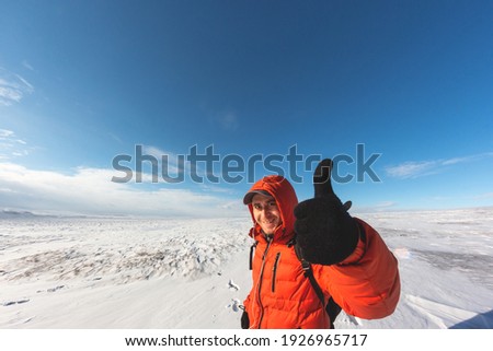 The guy with the briefcase on the background of the snowy horizon. Holds thumbs up