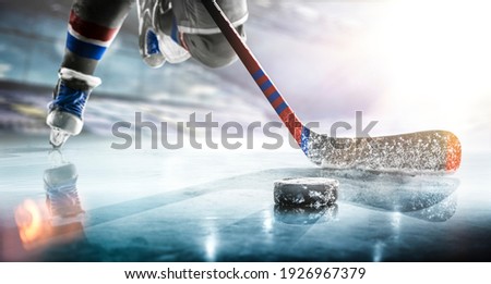 Close up of ice hockey stick on ice rink in position to hit hockey puck. Royalty-Free Stock Photo #1926967379