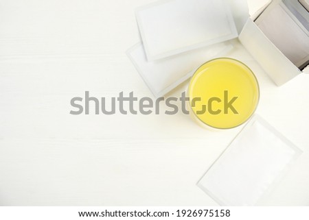 Medicine sachets and glass with dissolved drug on white table, flat lay. Space for text