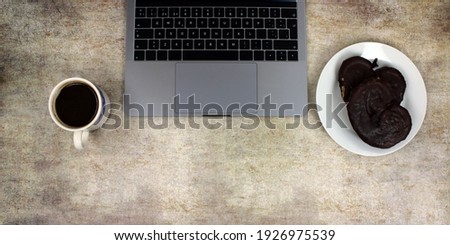 Portable computer in front of a coffee breakfast and chocolate pastries