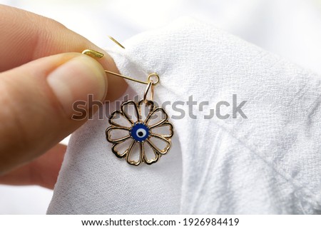 Woman pinning evil eye amulet on clothing, closeup