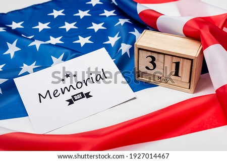Wooden calendar and card with memorial day lettering on american flag on grey background 