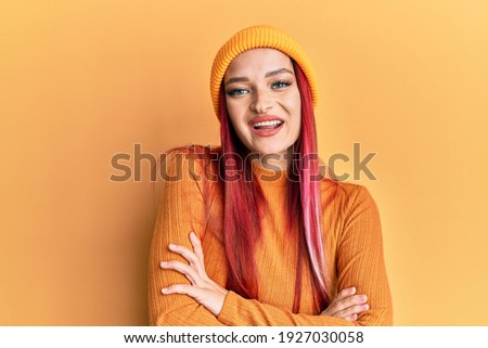 Young caucasian woman wearing wool cap happy face smiling with crossed arms looking at the camera. positive person. 