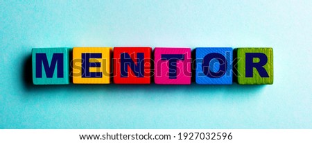 The word MENTOR is written on multicolored bright wooden cubes on a light blue background