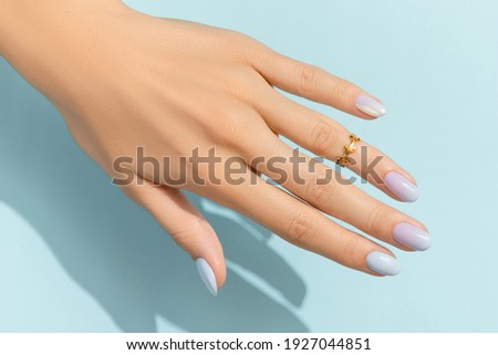 Womans hands with trendy manicure on blue background. Summer nail design Royalty-Free Stock Photo #1927044851