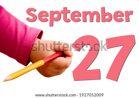 Children's hand writes September 27 in red pencil on white background. Business and leisure concept