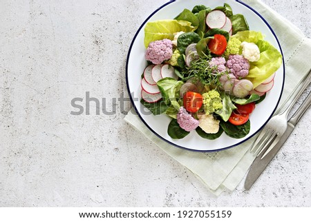 Raw vegetable salad with colorful cauliflower, lettuce, radish and tomato. Selective focus