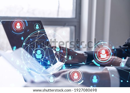 Two HR specialists analyzing the recruitment market using laptop to boost the intern program at international consulting company. Social networking hologram icons. Royalty-Free Stock Photo #1927080698