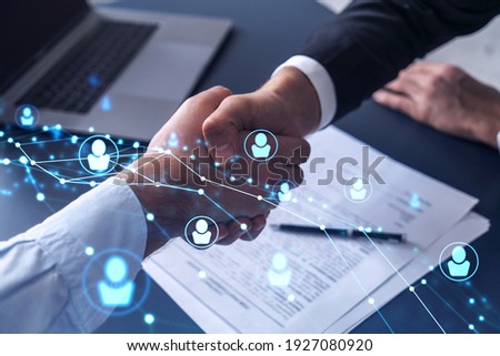 Recruitment concept to hiring of a new talented specialists for international company. Handshake to sign in of employment agreement. Social media hologram icons over the table with documents. Royalty-Free Stock Photo #1927080920