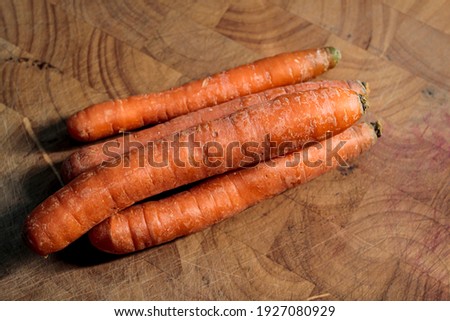 A few raw carrots on a wooden board.