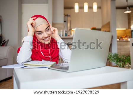 Young woman in hijab having video conference at home, using headset and laptop, drinking coffee, empty space. Online Education For Muslim Women. Happy Arabic Girl In Headscarf