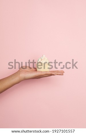 Holiday cupcake in female hand on pastel pink background. Minimal background composition