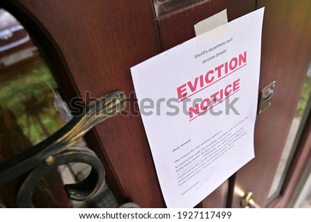 the notice of eviction of tenants hangs on the door of the house, front view Royalty-Free Stock Photo #1927117499