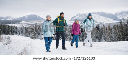 Family with small daughters on a walk outdoors in winter nature, Tatra mountains Slovakia.