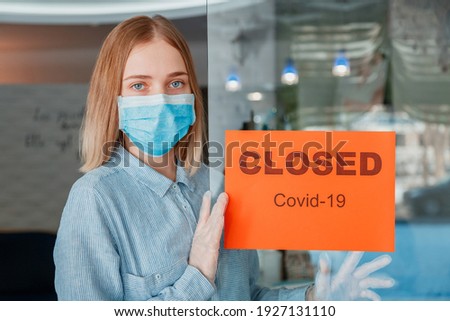 Sign closed Covid 19 on shop entrance door as new normal shutdown. Woman Business owner portrait in protective medical mask gloves hangs closed sign on front door of cafe. Lockdown coronavirus covid.