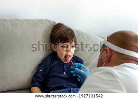 Caucasian boy having PCR test during coronavirus pandemic. Doctor takes a cotton swab test from child mouth to analyse for covid-19. Pediatrician using a swab to take a sample from a patient's throat.