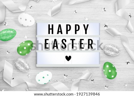 Lightbox, eggs, ribbons, stars on a wooden background. Text frame of the lightbox with the inscription Happy Easter with heart. Advertising mockup for Easter holiday. Top view, close up, copy space