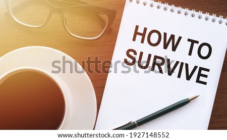 HOW TO SURVIVE - text on paper with cup of coffee and glasses on wooden background in sinlight.
