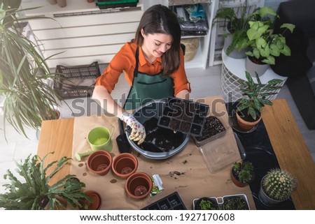 A happy young woman enjoys time at her homegarden. Seed-starting plants in the winter and early spring Royalty-Free Stock Photo #1927170608