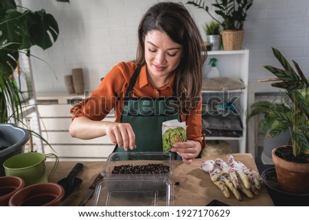 A happy young woman enjoys time at her homegarden. Seed-starting plants in the winter and early spring Royalty-Free Stock Photo #1927170629