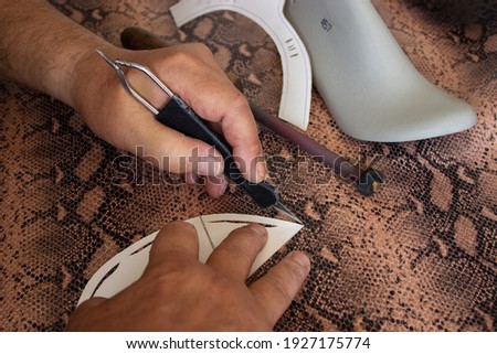 Shoemaker's hands cut leather and produce shoes