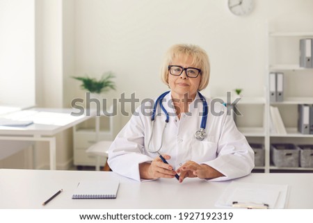 Friendly senior female doctor provides online counseling and communicates with her patients using a computer webcam. Portrait of an experienced doctor who keeps up with modern technology.