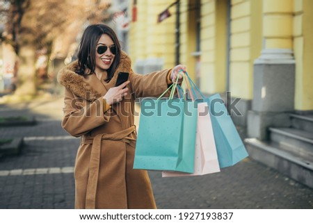 Shot of a young hispanic woman out shopping in the city while taking picture of the shopping bags with her smartphone