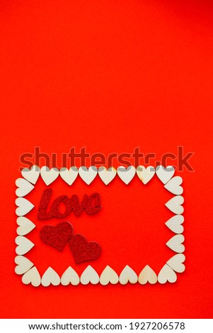 Valentine's day background. Wooden hearts are lined with rectangle on a red background with place for text with hearts. Hearts for postcards.