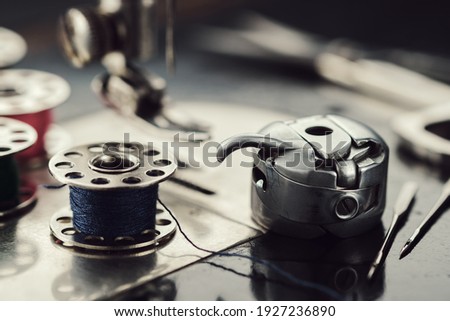 Working part of antique sewing machine. Selective focus on spool of thread, metal shuttle and sewing needles. Royalty-Free Stock Photo #1927236890