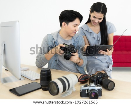 Asian man photographer viewing work ideas from the portfolio In order to work in accordance with the satisfaction of the model working atmosphere cozy smilling and happy. Concept photography camera