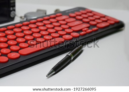 A Red And Black Keyboard, A Black Elegant Ball Pen, A Black Smartphone and A Steel Watch Isolated with White Background For Business Purposes 