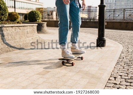 Young handsome woman riding on a skateboard. Portrait of sport female model in urban style. Skateboarding at city. Street style outfit. Urban woman ride on skate. Hipster girl on skateboard.